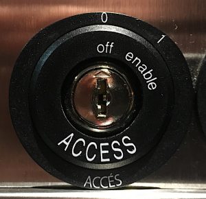 Elevator key hole with small words off and enamble around the edge, and access in capital letters