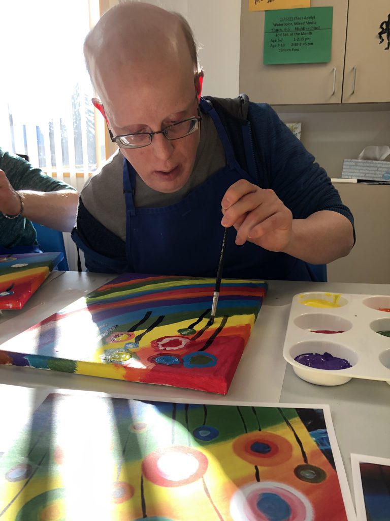 close up of one male Club Create Swartz Creek member carefully working on his painting