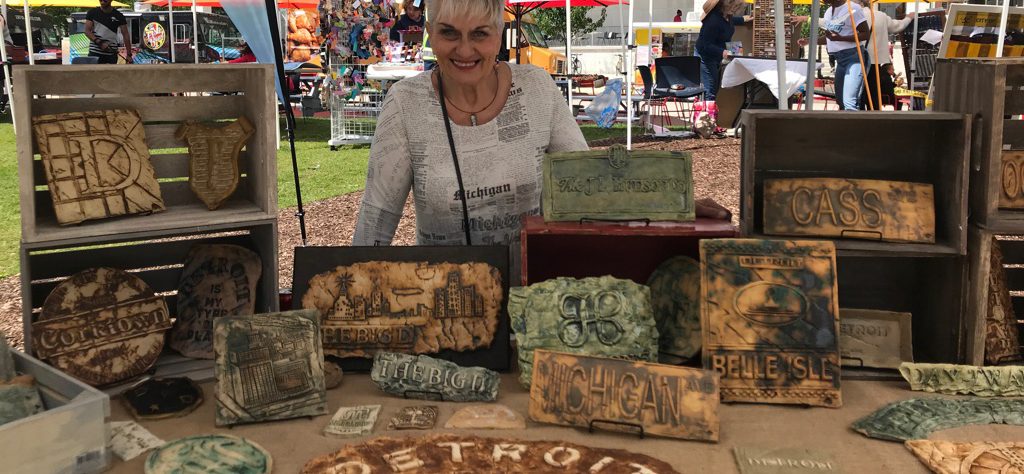 Debbie LaPratt in front of a table in her booth at an art fair with her ceramic artwork