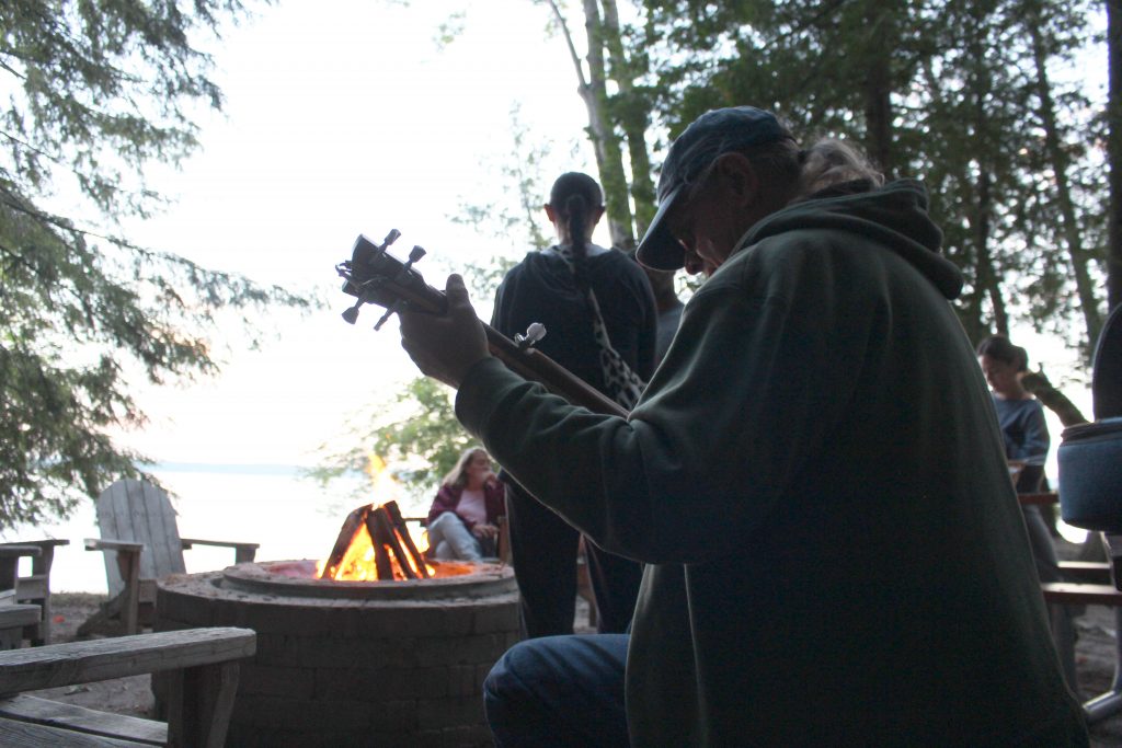 Attendee plays his guitar by the fire. 