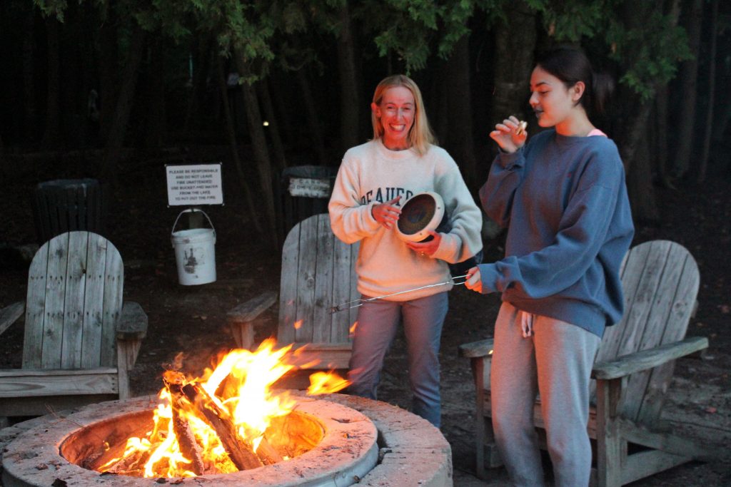 Participants playing a drum to the beat of the music and eating s'mores. 