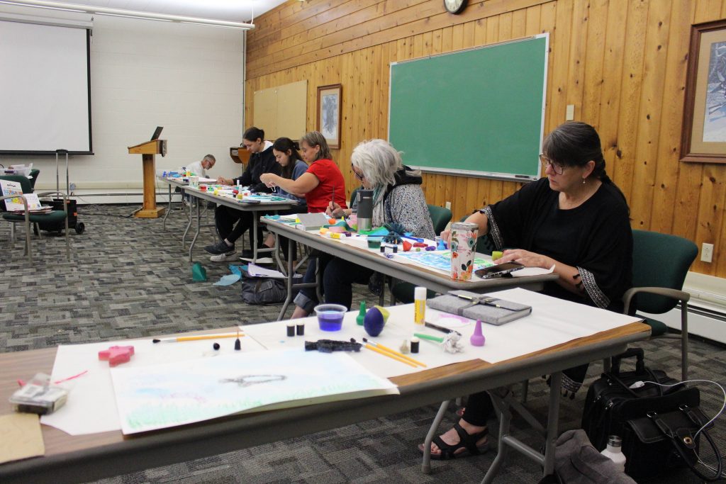 Attendees working with and using the art materials from a presentation.