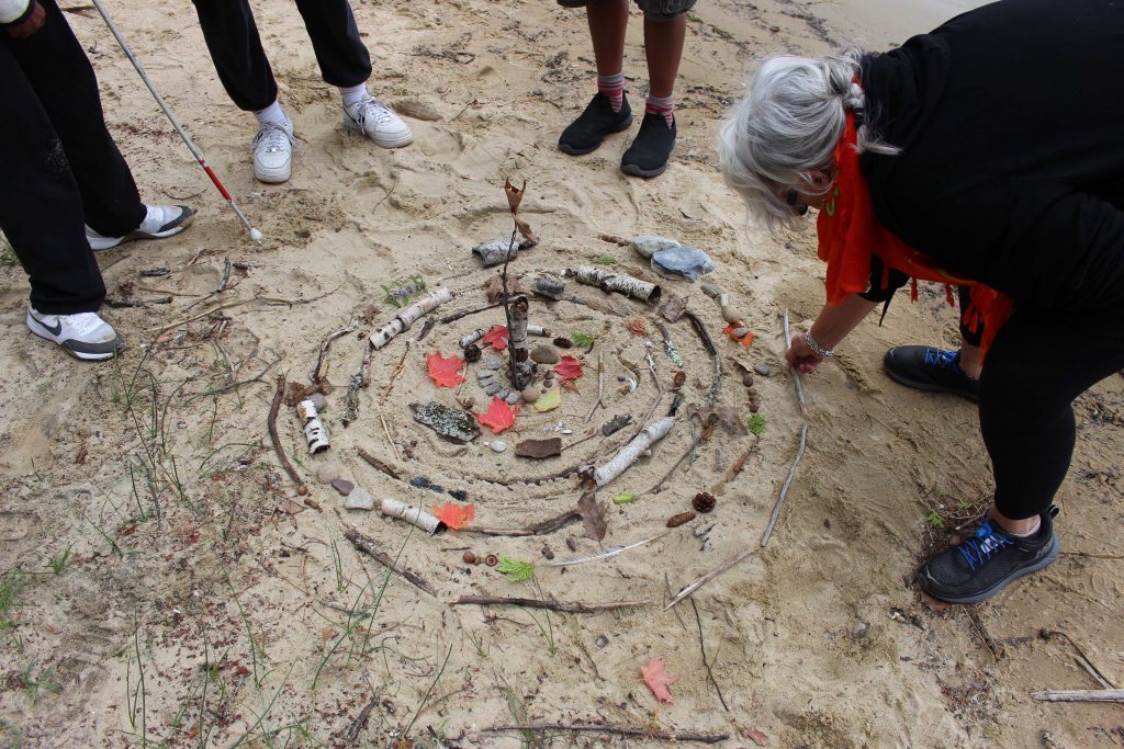 Attendees adding to the Mandala in the sand. 