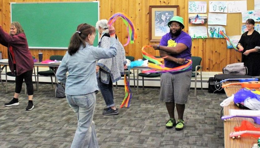 2 people facing each other moving creatively with colorful gymnastic ribbons